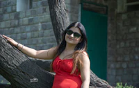 a woman in a red dress leaning against a tree
