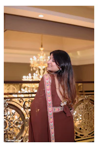 a woman in a brown sari standing in front of a chandelier