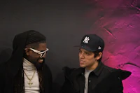 two men standing next to each other with hats on