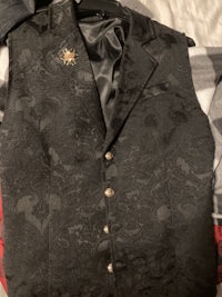a black vest with lace and buttons on a bed