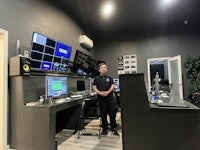 a man standing in front of several monitors in a recording studio