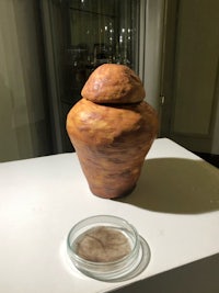 a ceramic jar on a table next to a glass