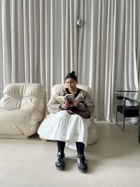 a woman sitting on a white couch reading a book