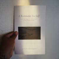 a hand holding a book with the title a reminder to self