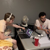 two men sitting at a table with a laptop