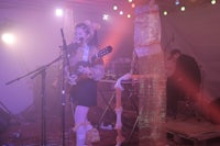 a woman is playing a guitar in front of a microphone