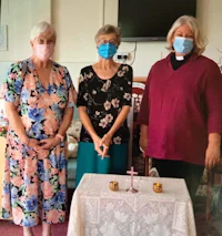 three women wearing face masks standing in front of a table