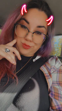 a woman wearing glasses and a plaid shirt in a car