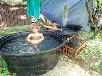 two men are sitting in a tub next to a tent