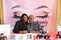 two women are posing for a photo at a booth