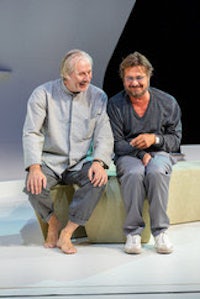 two men sitting on a bench on stage