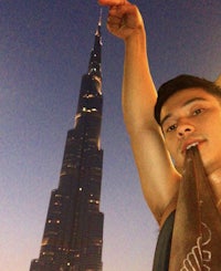 a man posing in front of the burj khalifa