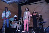 a group of people singing on stage in front of a wooden wall