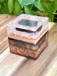 a square glass box with sand and rocks inside