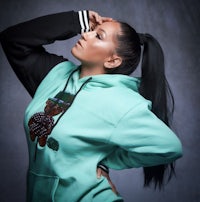 a woman wearing a green hoodie with a teddy bear on it