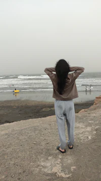 a woman standing on a beach with a surfboard