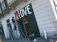 a man on a ladder is working on a sign that says love