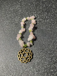 a necklace with a pink stone and a gold charm