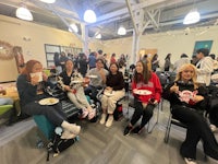 a group of people sitting in a room with plates of food