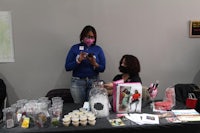 two women standing at a table with a lot of items on it
