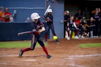 a softball player swinging at a ball during a game