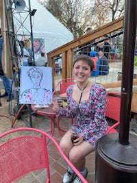 a woman sitting at a table holding a drawing