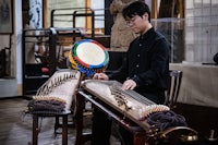 a man playing a chinese instrument in a museum