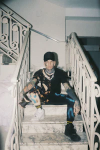 a man sitting on stairs with tattoos on his legs