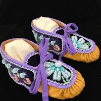 a pair of moccasins with purple and blue beads
