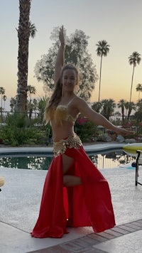 a woman in a red dress is dancing in front of a pool