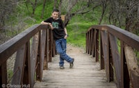 a young man posing on a wooden bridge