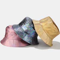 three holographic bucket hats on a white surface