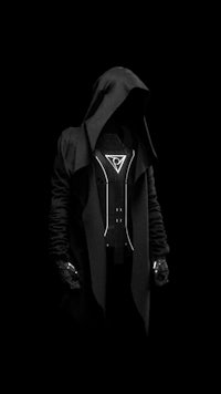 a man in a hooded coat is standing in a dark room