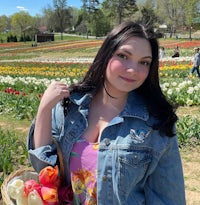 a woman in a denim jacket standing in a field of tulips
