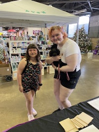 two women standing next to each other at a craft show