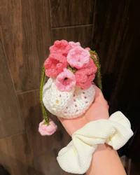 a person holding a small crocheted flower bag