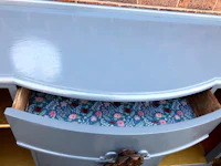 a blue painted dresser with a floral pattern