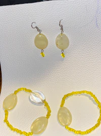 a yellow beaded bracelet and earrings on a table