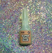 a bottle of super nail glue on a glittery background