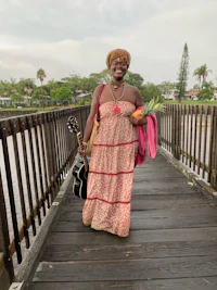 a woman in a dress standing on a bridge with a guitar
