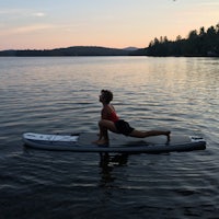 a woman doing yoga on a paddle board in the water