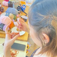 a woman is knitting a hat with yarn in front of a table