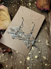 a pair of silver earrings on a piece of paper