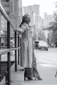 a black and white photo of a woman leaning on a railing