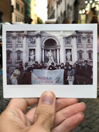 a person holding up a photo of people in front of a building
