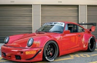 a red porsche 911 gt3 parked in front of a garage