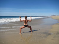 a woman in a bikini doing yoga on the beach