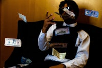 a man sitting in a chair with money flying around him