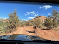 the view from the driver's seat of a vehicle on a dirt road
