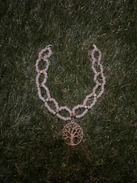 a necklace with a tree of life in the grass